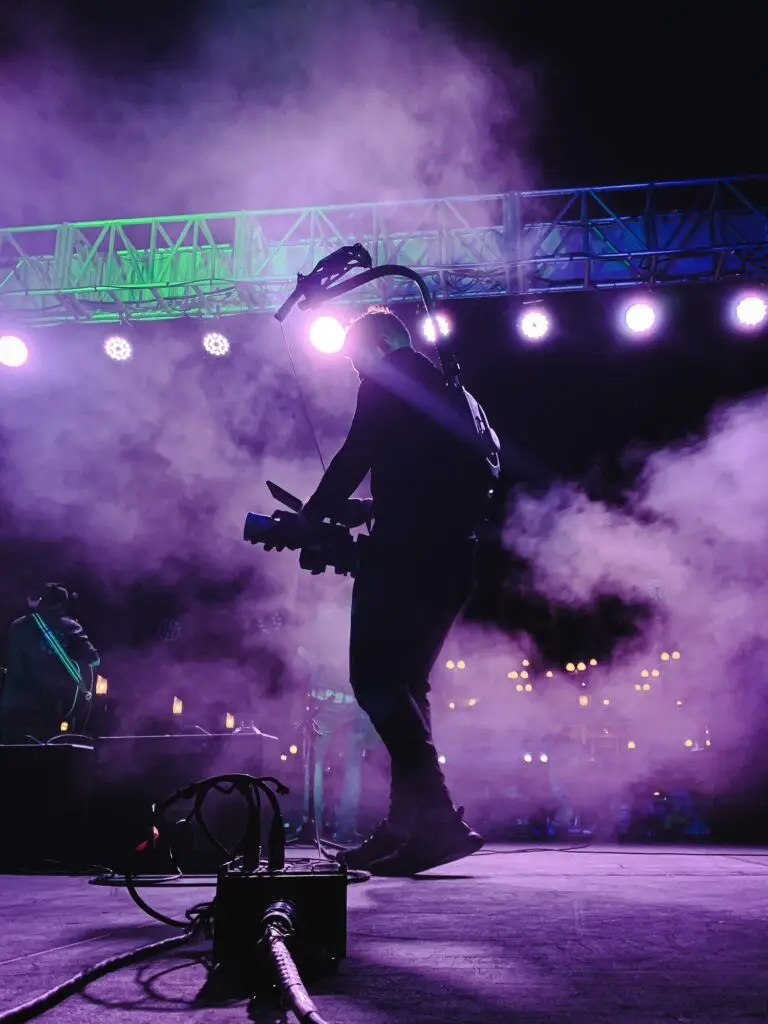 A videographer onstage at a concert filming a band